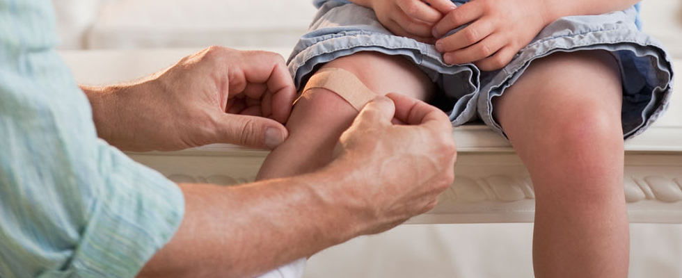 Person apply a plaster on a child's knee